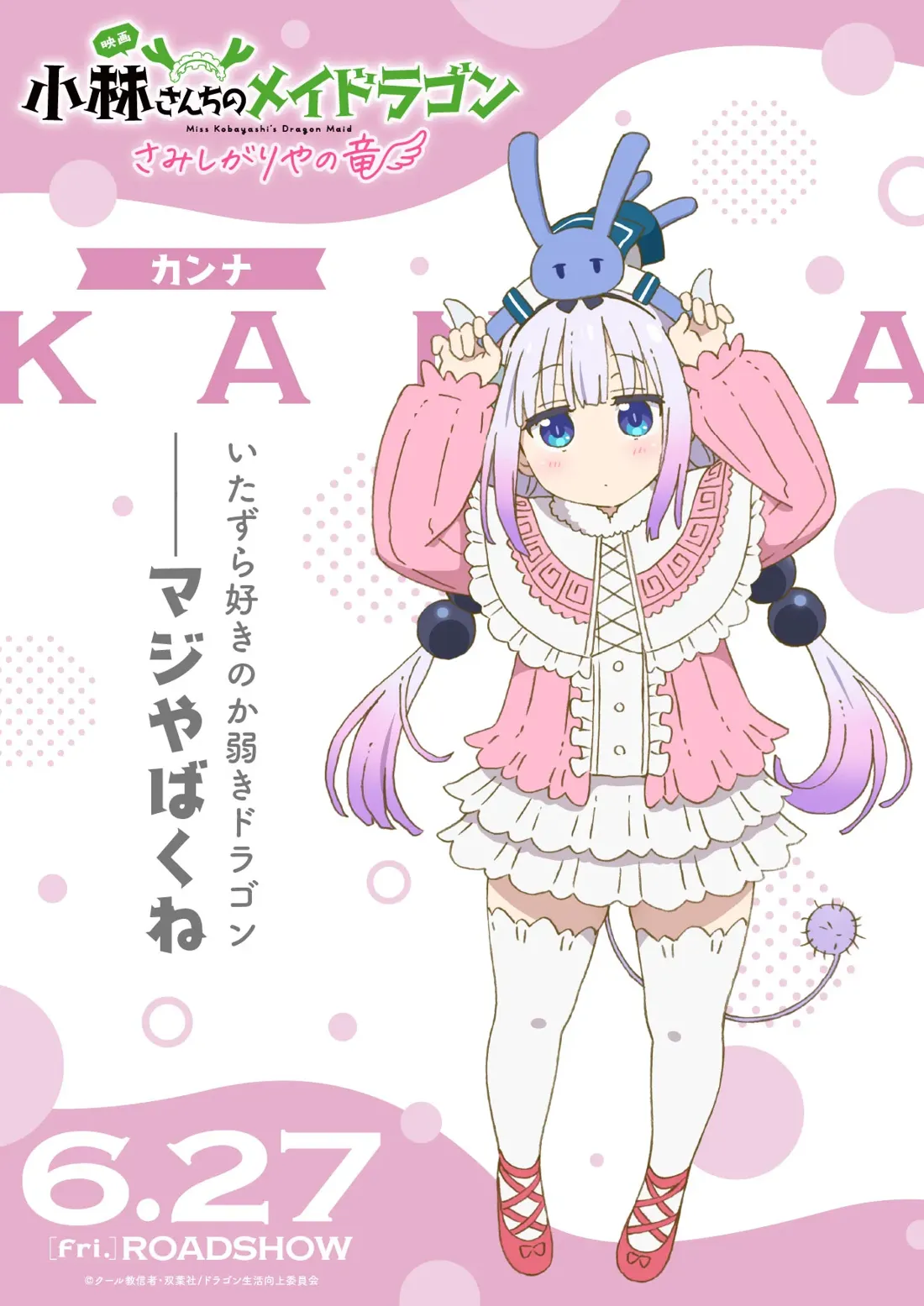 Promotional poster for the anime film 'Miss Kobayashi's Dragon Maid: Can't Be Helped, Tooru!', featuring Kanna Kamui.  Kanna, a young, light-skinned dragon girl, is depicted in a cheerful pose, playfully holding a small blue bunny-eared plushie on her head. She's wearing a pink cardigan over a white dress with ruffled trim, white thigh-high socks, and red Mary Jane shoes. Her long, pale lavender hair hangs down her back. The background is a light pink and white design with stylized circles and the film's title in Japanese and English, along with the release date: 6.27. The overall style is anime, characteristic of lighthearted and whimsical character designs.